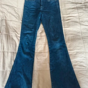 Blå utsvängda jeans från J.Lindeberg - Säljer ett par blå jeans från J.Lindeberg med utsvängda ben. De är i en perfekt lite mörkare tvätt.
