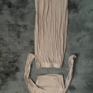 Beige långklänning med lång ärm - Säljer en beige långklänning med långa ärmar. Klänningen har en enkel och stilren design med rund halsringning och är tillverkad i ett mjukt material som faller snyggt längs kroppen.