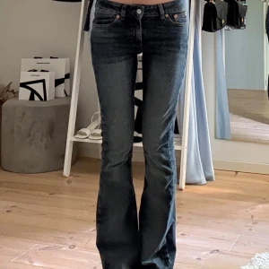 Mörkblå bootcut jeans från Junkyard - Snygga mörkblå jeans från Junkyard med bootcut passform och klassiska fickor. Jeansen har låg midja och en liten logopatch bak i midjan. Perfekta för dig som gillar en tidlös stil med lite utsvängda ben. Nypris 600 och bara använt ett få tal gånger.
