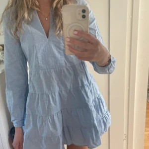 Ljusblå klänning zara - Säljer en super söt ljusblå klänning med volanger och lång ärm. Klänningen har v-ringning och en lös passform, perfekt för varma dagar. Den är i storlek S, säljer då den inte längre kommer till användning. Som ny!