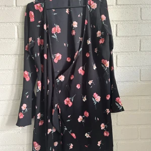 Svart klänning  - En svart klänning med blommor och knyte Använd fåtal gånger så den ser relativ ny ut Storlek 44/XXL Säljer då den är för stor för mig Hör av er om frågor eller mer bilder!🌷