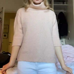 Ljusrosa stickad polotröja från Indiska - Mysig ljusrosa stickad polotröja från Indiska. Tröjan har halvkort ärm, hög polokrage och rak passform. Perfekt för lager-på-lager och enkel att styla till olika outfits.