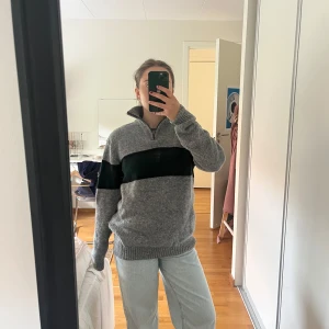 Brandy Melville Tröja - Säljer en grå stickad tröja med halv dragkedja i halsen och en bred mörkgrön rand över bröstet från brandy Melville. 