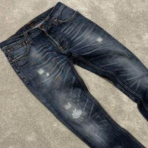 Nudie Grim Tim - Tja! Säljer dessa riktigt feta blå/grå Nudie ”Grim Tim” jeansen med riktigt najs tvätt och schyssta slitningar! Jeansen är i fint skick. Size 32/32. Skriv vid funderingar!
