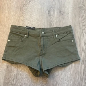 Olivgröna jeansshorts - Snygga olivgröna jeansshorts med fem fickor och knappgylf. Klassisk design med bälteshällor och låg midja. Perfekta för varma dagar och enkel att matcha med olika toppar.