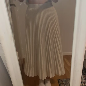 långkjol - Säljer en snygg beige plisserad långkjol med hög midja från H&M. Kjolen har ett elegant fall och är perfekt för dig som gillar en stilren och klassisk look. Passar till många olika outfits och är superenkel att styla. Den har bara använts en gång! Säljer pågrund av jag byter stil hela tiden 🫶 kontakta för mer information 