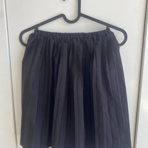 Svart plisserad kjol - Säljer en svart plisserad långkjol med resår i midjan. Kjolen har en klassisk och enkel design med fina veck som ger ett snyggt fall. Perfekt att styla med en t-shirt eller stickad tröja. Pris kan diskuteras.