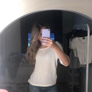 Vit stickad topp med puffärm från Bik Bok - Säljer en söt vit stickad topp från Lindex med puffärmar och rund halsringning. Toppen har ett diskret mönster i materialet och trekvartsärmar. Perfekt för dig som gillar en feminin och stilren look.