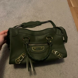 Mörkgrön handväska  - Säljer grön handväska. Använd 2 gånger. Rostet på framsidan var redan där när jag köpte den. Säljer för 700kr