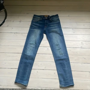 Blå Jack and Jones jeans - Säljer ett par Jack and Jones jeans som är av modellen Tapered Mike. Byxorna är i mycket bra skick och har en skön tvätt. Storlek 28W 32L