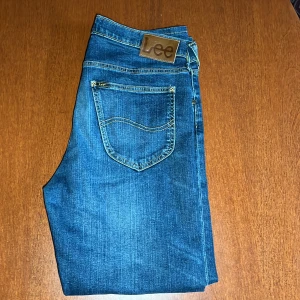 Blå jeans från Lee - Klassiska blå jeans från Lee med femficksdesign och Lee-lapp bak i midjan. Jeansen har raka ben och normal passform, tillverkade i slitstarkt denimtyg. Perfekta för en avslappnad stil.      W33. L36