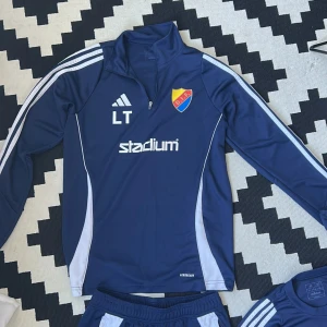 Tränings set från Adidas med DIF-logga - Mörkblå överdelar, träningsbyxor och två par t shirts från Adidas med vita ränder längs sidorna och DIF-emblem på låret. Knappt använda och säljs som ett set 4 grejer för 500kr. Tröjan och byxorna är sålda 