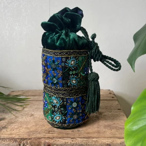 Grön broderad väska med pärlor och paljetter - Unik handgjord grön väska i sammet med broderade detaljer, pärlor och paljetter i blått och guld. Väskan har dragsko upptill och dekorativ tofs. Perfekt för dig som vill sticka ut med en färgstark accessoar. Oanvänd men några snören sticker ut från banden.