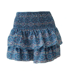 Blå mönstrad volangkjol - Supersöt blå kortkjol med elastisk smock i midjan och volanger. Kjolen har ett detaljerat mönster i blått, vitt och inslag av rosa. Perfekt för dig som vill ha en unik kjol men ändå känna dig bekväm då det på insidan finns shorts!!