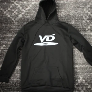 DVD Y2K Hoodie Huvtröja Smal - Säljer en svart hoodie med stor vit VD-logga på bröstet. Klassisk känguruficka framtill och justerbar huva med dragsko. Perfekt för en avslappnad och stilren look.