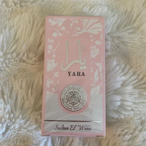 Yara parfym från Sultan El Waha - Säljer en parfym vid namn Yara från Sultan El Waha. Förpackningen är ljusrosa med vita dekorativa mönster och text i både arabiska och engelska. Flaskan innehåller 100 ml Eau de Parfum och har en elegant och feminin design. 💕