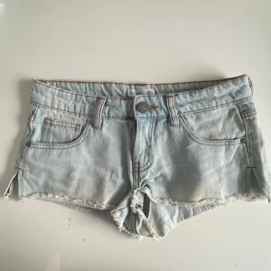 Ljusblå jeansshorts från Sinsay - Snygga ljusblå jeansshorts från Sinsay med fransig kant och klassisk femficksmodell. Shortsen har låg midja, knapp och dragkedja framtill samt råa kanter för en avslappnad look.