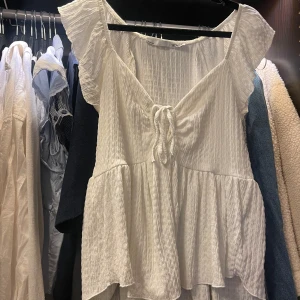 Vit blus med volangärm och knytning - Söt vit blus med volangärmar och knytning framtill. Den har en lös passform och är endast använd några fåtal gånger 🤍