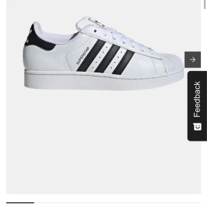 Adidas Superstar vita sneakers - Klassiska Adidas Superstar sneakers i vitt med svarta ränder och snörning. Skon har rund tå, platt sula och ikonisk shell-toe design. Perfekt för dig som gillar en tidlös och sportig stil. Nypris: 1 500kr 💝