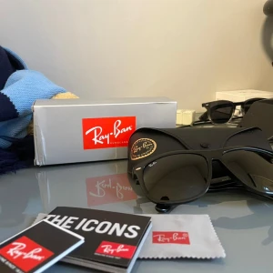 Svarta solglasögon från Ray-Ban - Klassiska svarta solglasögon från Ray-Ban med Wayfarer-form. Glasögonen har mörka linser och diskret Ray-Ban-logga på linsen och skalmen. Tillverkade i Italien och levereras med originalförpackning och putsduk.