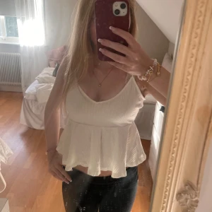 Vit ribbad linnetopp med volang - Säljer en söt vit linnetopp med smala axelband och volang nertill. Toppen är ribbad och har en v-ringad halsringning. 💕