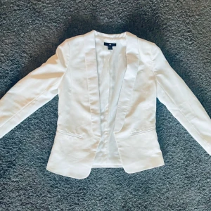 Snygg vit partykavaj - En riktigt fin kavaj utan knäppning som sitter oerhört snyggt. Perfekt för sommarens alla fester