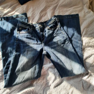 Blå jeans med raka ben - Säljer ett par klassiska blå jeans med Flared ben. Jeansen har en snygg tvätt med slitningar och kontrastsömmar. Perfekta för en avslappnad och cool stil.