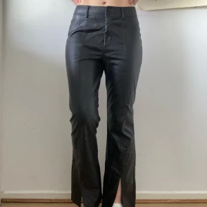 Svarta skinnbyxor från Topshop - Snygga svarta skinnbyxor från Topshop med hög midja och bootcutmodell. Jättebraskick förutom det lilla skavet som syns på bild. 