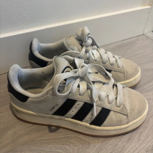 Adidas Campus 00s - Snygga Adidas Campus 00s i beige mocka med klassiska svarta ränder på sidorna och gummisula. Storlek 36!