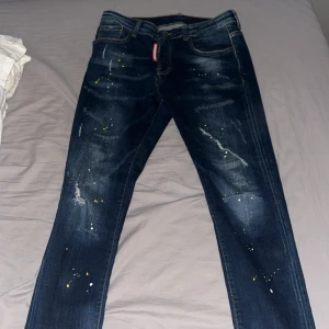 Mörkblå jeans med färgstänk - Ett par snygga dsquared 2 jeans med mycket detaljer. Det står storlek 46 på byxorna som oftast motsvarar S-M. Medie mått ca: 80cm. (US storlek w30-31)