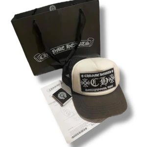 Chrome Hearts truckerkeps - Säljer en beige och svart truckerkeps från Chrome Hearts med stor broderad patch framtill och mesh baktill. Kepsen har justerbar passform och tydliga logodetaljer både inuti och utanpå. Har kvitto från butik samt påsen och tändstickorna man får med. I använt skick
