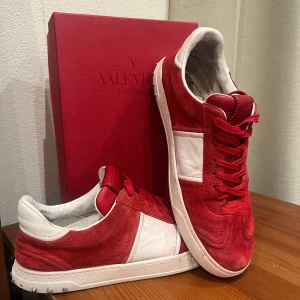 Valentino Garavani röda och vita sneakers - Valentino Flycrews, skick 8/10 lite sliten i skorna men inget man tänker på när du använder dom! Storlek 43 men passar +- 1 storlek, bara 1 nit som saknas, har nitar men det är Tyvärr inga OG nitar, om ni har några frågor är det bara att DMa! 🙌🏻