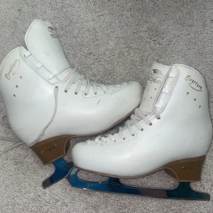 Vita konståkningsskridskor från Edea - Säljer ett par vita konståkningsskridskor från Edea med John Wilson-blad. Klassisk modell med snörning och rund tå. Perfekta för dig som vill satsa på konståkning eller bara åka för skojs skull. Bladen är tillverkade i Sheffield, England. Storleken är ca 34-35, men är svårt att säga exakta storlek. De passade dock inte min dotter som har 36-37 då dom var för små. Har varit tejpade så dom är i fint skick. Då det finns lite små skrapor här och där. Har använts ett få tal gånger förut. 
