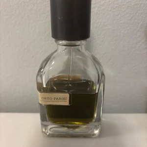 Stercus parfym från Orto Parisi - Exklusiv parfymflaska från Orto Parisi med doften Stercus. Flaskan har en elegant och robust design med en mörk kork och en etikett i beige. Perfekt för den som söker en unik och djärv doftupplevelse. 29 ML kvar av 50ML