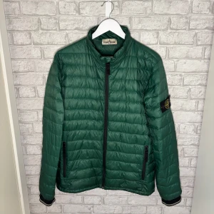 Stone Island jacka - Stone Island lättviktsjacka i grön färg. Quiltad modell med dragkedja och tryckknappar. Detta är en äldre modell, producerad innan Certilogo/QR-systemet infördes 2014. Använd men i fint skick. Inga hål eller större defekter. Fler bilder kan skickas i pm, hör av dig vid intresse 🙌