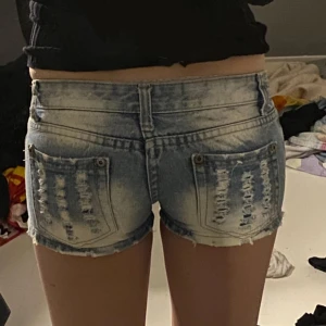 Lågmidjade jeansshorts med slitningar - Säljer ett par ljusblå, mycket lågmidjade jeansshorts med slitningar. 