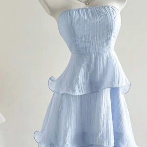 Ljusblå axelbandslös volangklänning - Superfin ljusblå klänning med axelbandslös design och flera lager volanger. Klänningen har en lätt och luftig känsla, perfekt för varma dagar. Materialet är tunt och ger ett romantiskt intryck.