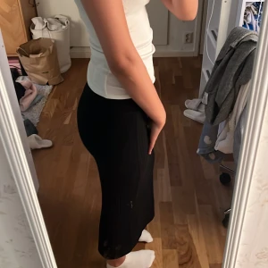 Svart långkjol i bomull - Säljer en svart långkjol i mjukt bomullsmaterial. Kjolen har en enkel och stilren design med rak passform och resår i midjan. Perfekt att matcha med olika toppar för en clean look.