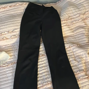 Svarta bootcut träningstights från H&M Move - Säljer ett par svarta bootcut träningstights från H&M Move i storlek XS. Byxorna har hög midja och är tillverkade i ett stretchigt syntetmaterial som passar perfekt för träning. Snygg och enkel design utan synliga detaljer.