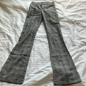 Rutiga kostymbyxor från Bershka - Säljer ett par snygga svartvita kostymbyxor från Bershka med klassiskt rutigt mönster. Byxorna har bootcut-modell med vida ben och normal passform. Perfekta för dig som gillar stilrena och trendiga plagg.