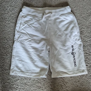 Sail Racing shorts - Säljer ett par vita shorts från Sail Racing med snörning i midjan och tryckt logga på ena benet. Shortsen har sidofickor och en bakficka. Perfekta för sommaren och riktigt sköna att ha på sig.