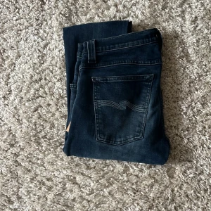 skinny jeans från Nudie Jeans - Snygga mörkblå skinny jeans från Nudie Jeans med diskreta slitningar. Jeansen har en smal passform och är tillverkade i mjukt bomullstyg med stretch. Bakfickorna har Nudie Jeans ikoniska broderi kan diskutera pris 