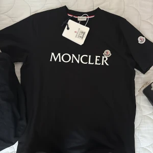 Svart Moncler T-shirt  - Säljer en svart T-Shirt från Moncler i storlek M. Super bra material, Fungerande NFC tag på armen. För fler bilder vid intresse fråga gärna.