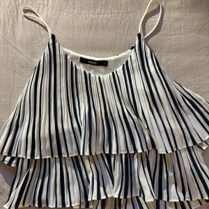 Randig volangtopp från BikBok - Säljer en vit och marinblå/randig topp från BikBok med tunna axelband och dubbla volanger. Storlek S, använd fåtal gånger. Kom med bud🩷