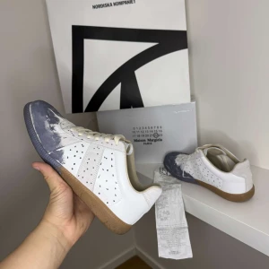 Maison Margiela GATS - Maison Margiela sneakers i mörkblått, kvitto låda och skor får man med vid köp. Skorna är 9/10 sick och är enbart lite smutsiga och repade under sulan vilket är naturligtvis meningen pris går att förhandla och skorna säljs i befintligt sick. Se sista bilden för att se kvittot. Innesulan är bytt från orginal till extra sulorna man får med när man köper dem vilket sänker priset en del!
