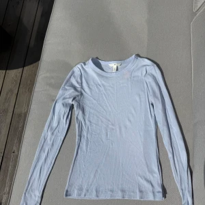 Ljusblå ribbad långärmad tröja från H&M - Säljer en ljusblå långärmad tröja från H&M. Tröjan är ribbad och har en tight passform med rund halsringning. Storlek M