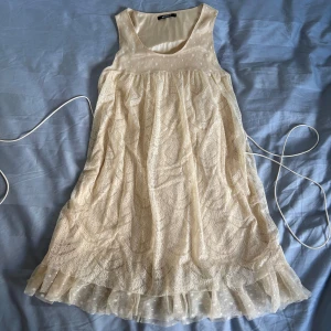 Vit spetsklänning med volangkant - En sjukt söt benvit klänning med spets och volangkant nertill. Klänningen har ett tunt band i midjan som kan knytas och ett skirt lager med prickigt tyg längst ner. Så drömmig och söt! Perfekt för studenten och sommaren 💐💐