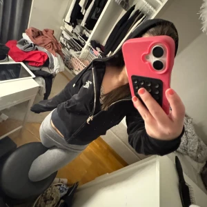 Svart hoodie från Juicy Couture - Säljer en svart hoodie från Juicy Couture med dragkedja och huva. Ikonisk Juicy Couture-logga i stenar på ryggen. Mjuk och skön, perfekt för en avslappnad stil. Klassisk passform och snygga detaljer framtill.