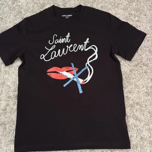 Svart t-shirt från Saint Laurent med tryck - Säljer denna saint Laurent tröjan(No smoking) för att jag ej använder den , inga defekt och e som ny. Priset går att diskutera(den passar både s/m