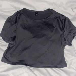 Grå  croppad t-shirt  - En enkel grå croppad t-shirt. Modellen har rund halsringning och korta ärmar. Perfekt att matcha med höga jeans eller kjol.